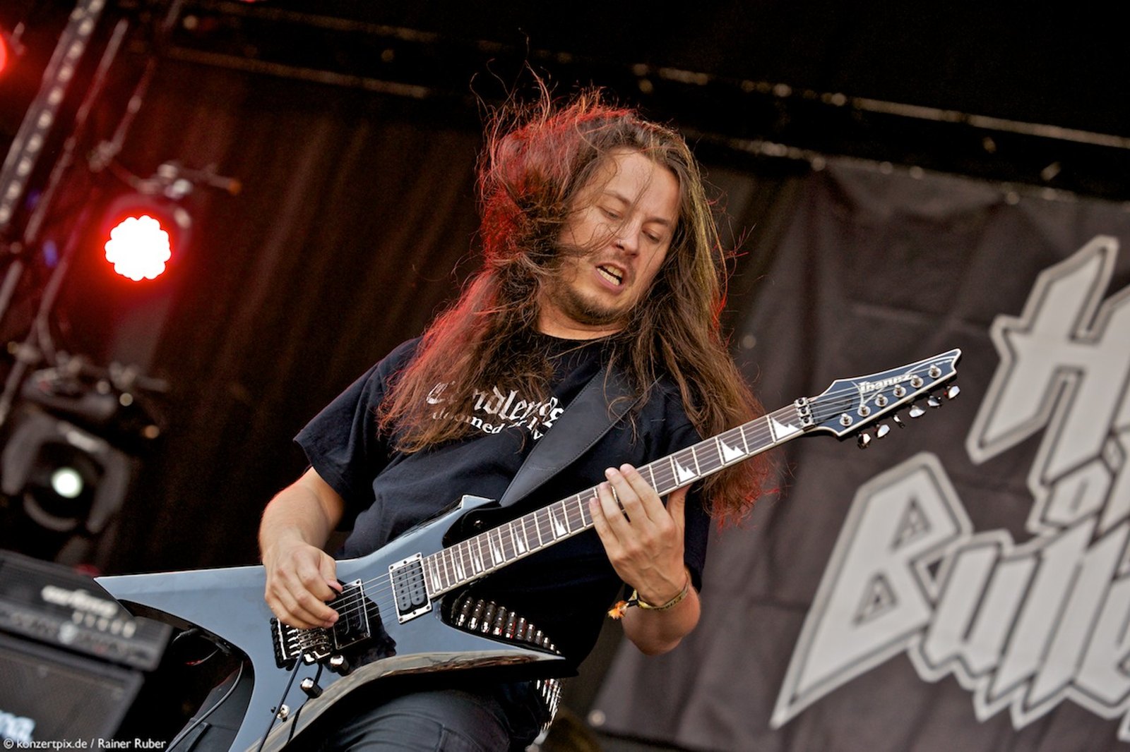 Hail of Bullets guitarist headbanging mid-riff on stage, red stage light behind him