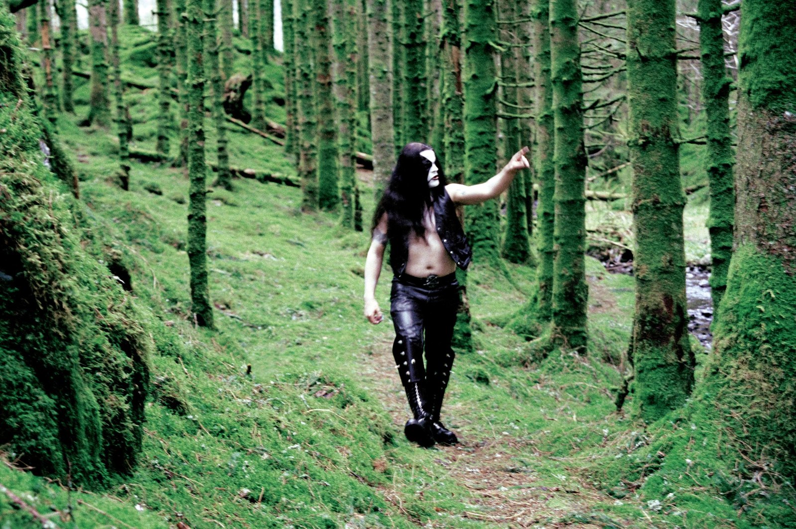 Abbath of Immortal walking through a mossy Norwegian forest in corpsepaint and battle gear