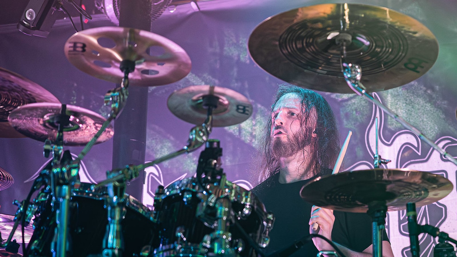 Decapitated's drummer behind a kit of Meinl cymbals at The Fleece in Bristol, stick raised, eyes up, with the band's logo banner behind him, 2023.