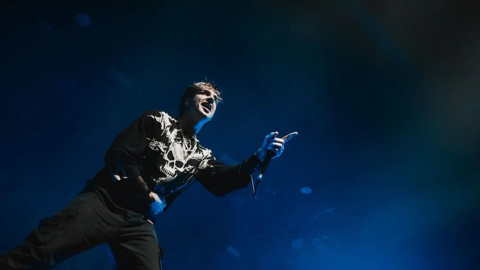 Alpha Wolf vocalist leaning out from the stage and pointing at the crowd, microphone in hand, in deep blue stage haze, Brisbane 2024