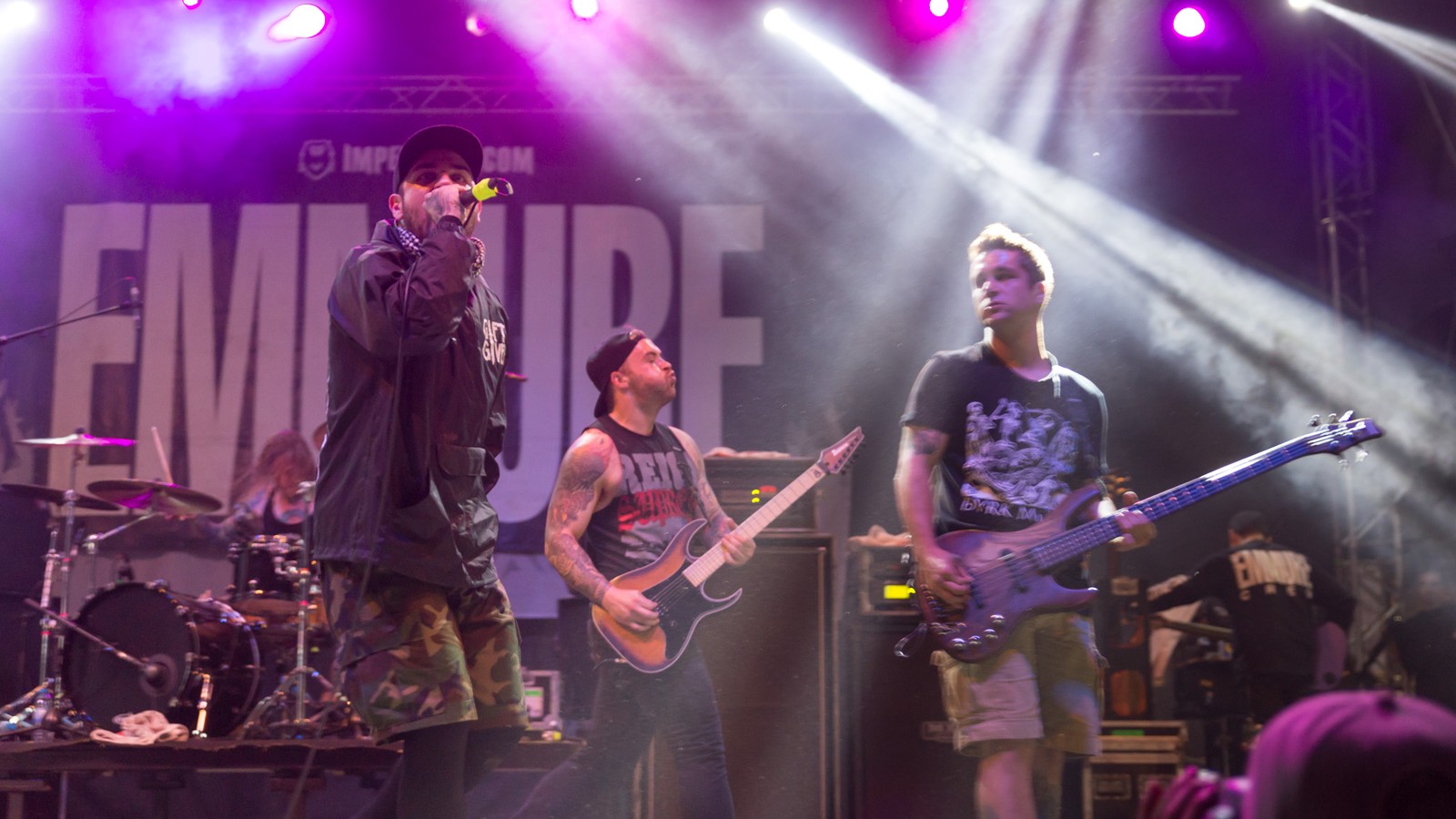 Emmure on stage at With Full Force 2014: the vocalist singing at the left, guitarist and bassist beside him and the drummer behind, in front of the band's logo backdrop under purple lights