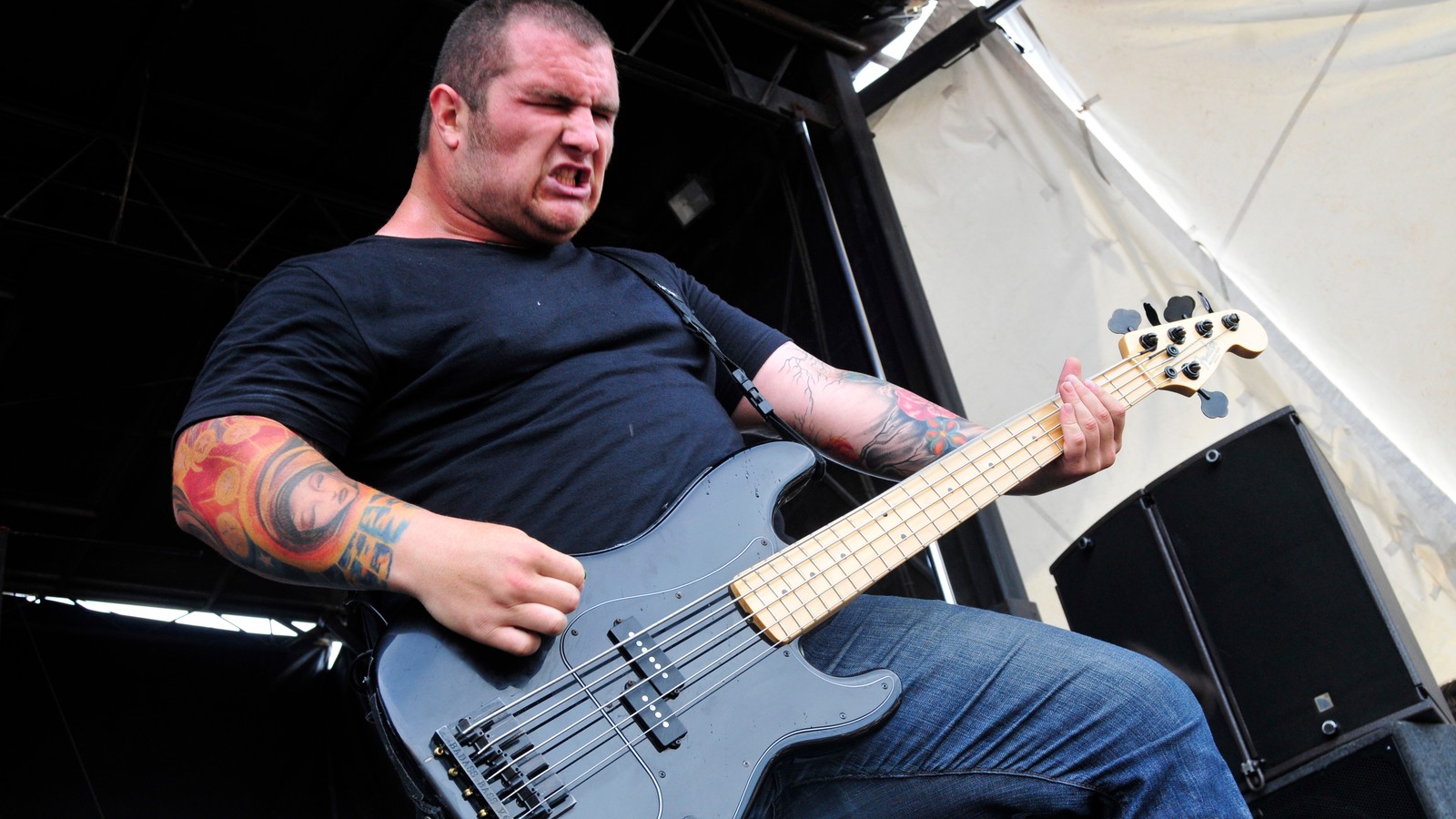 Whitechapel bassist Gabe Crisp playing a black bass on stage at Mayhem Festival 2009, shot from a low angle against the stage truss