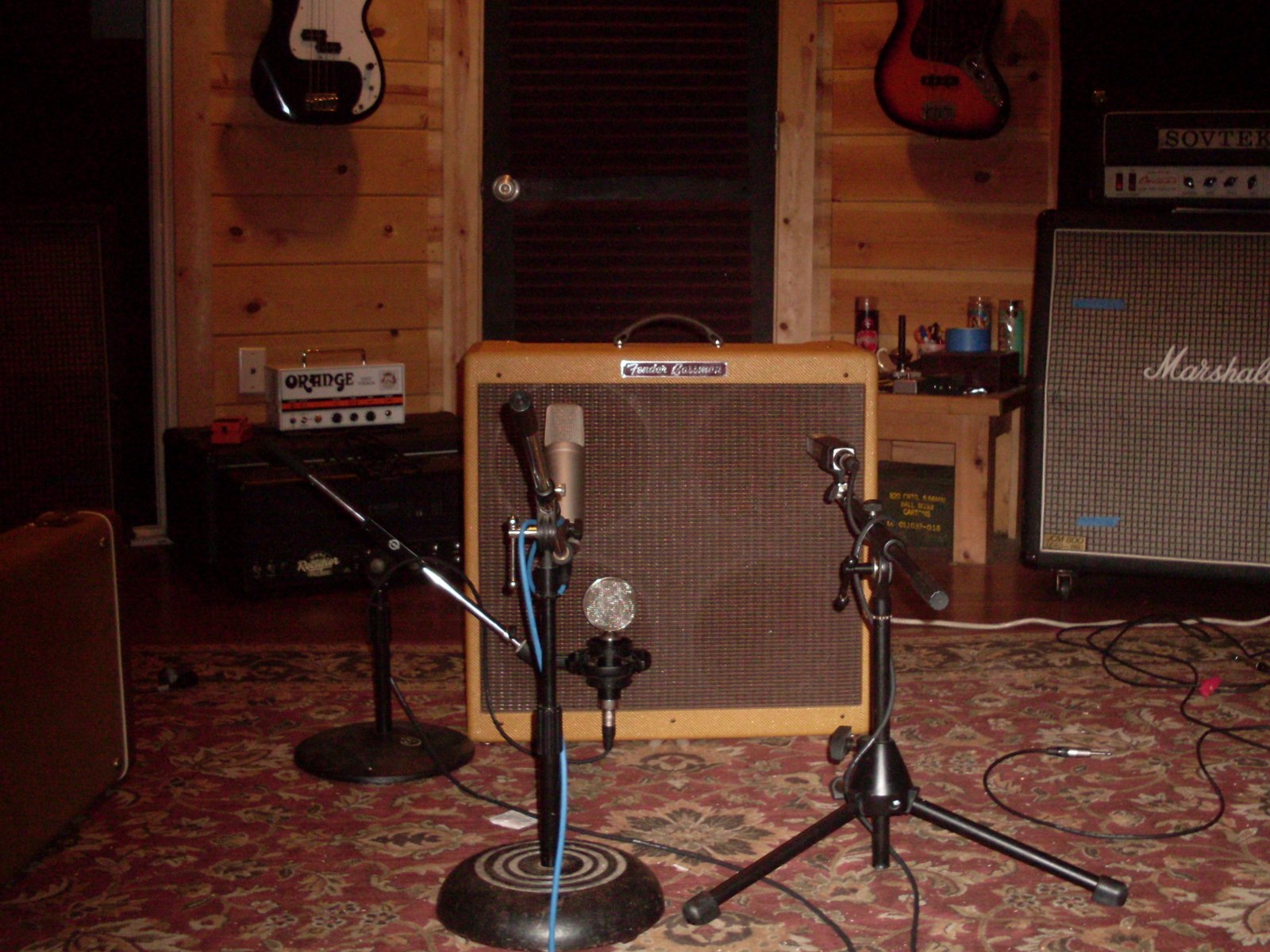 A Fender Bassman combo with two microphones on stands set in front of it in a studio live room
