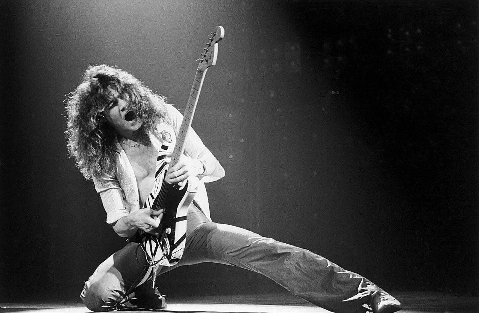 Eddie Van Halen playing live at the Rainbow Theatre, London, October 1978, fretting hand gripping the neck of his striped guitar