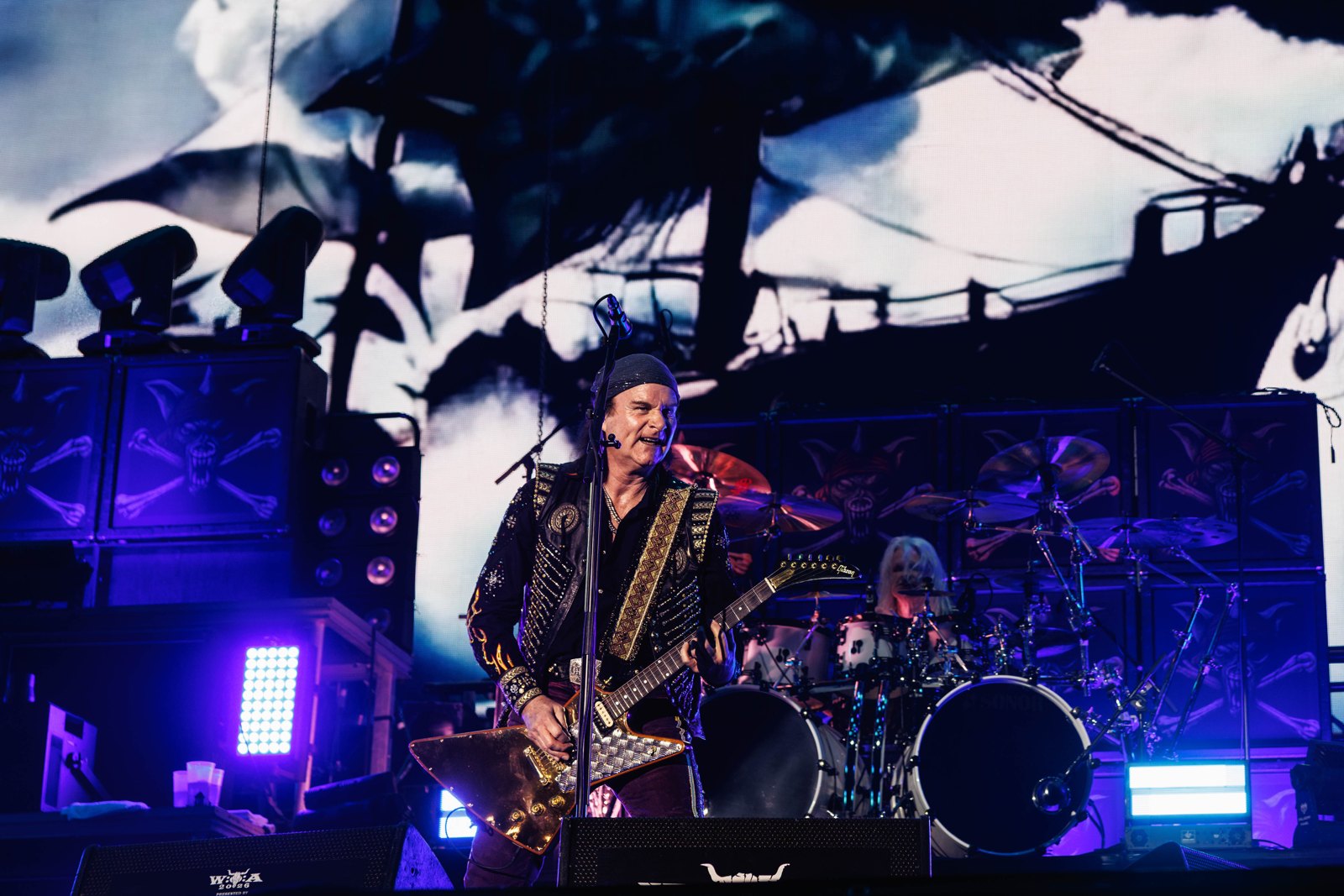Rolf Kasparek of Running Wild on stage at Wacken in August 2026, a gold Flying V in his hands and a pirate ship painted across the backdrop