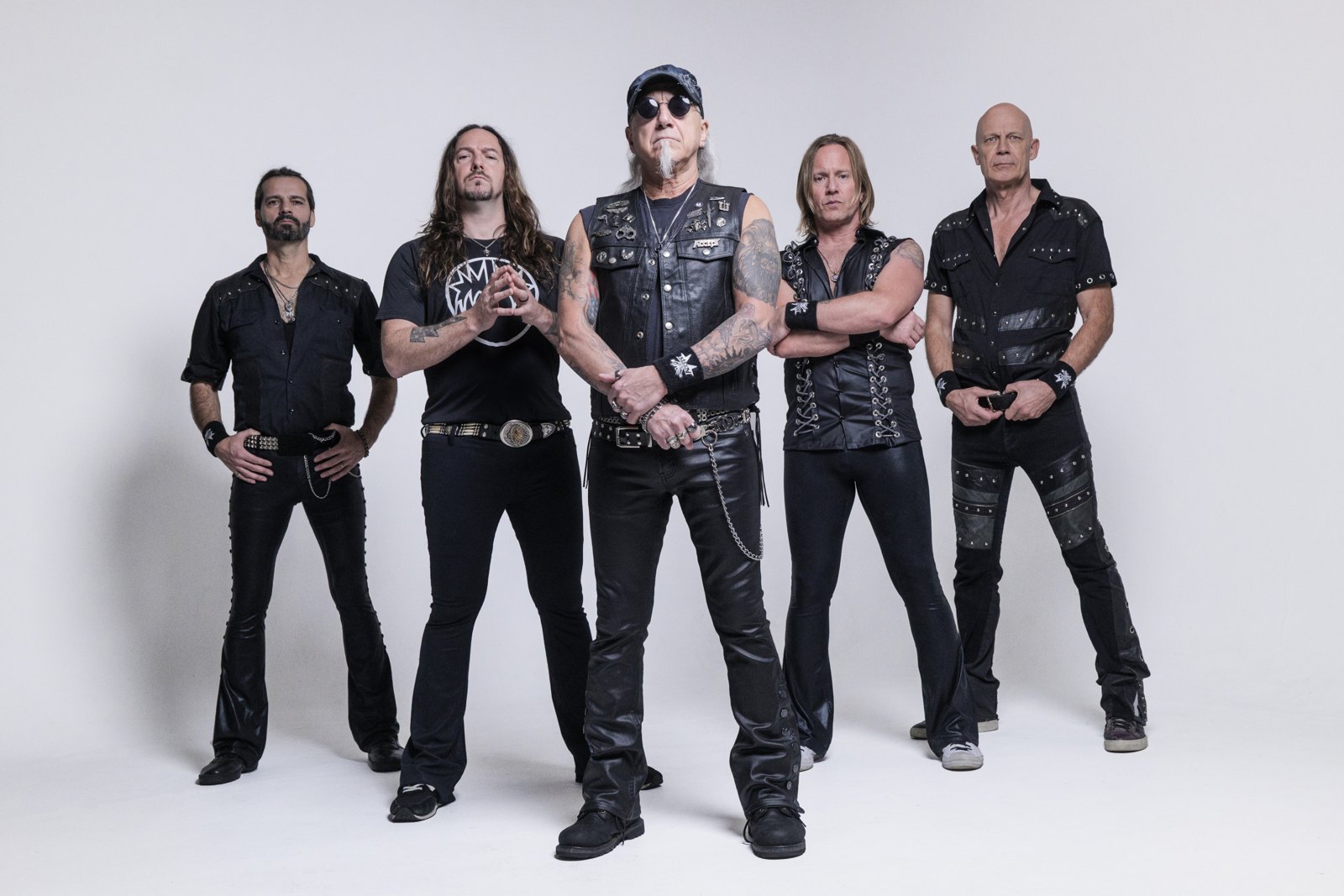 Accept, the German band behind Balls to the Wall, posed as a five-piece studio portrait in 2026, all in black leather and denim against a plain white backdrop