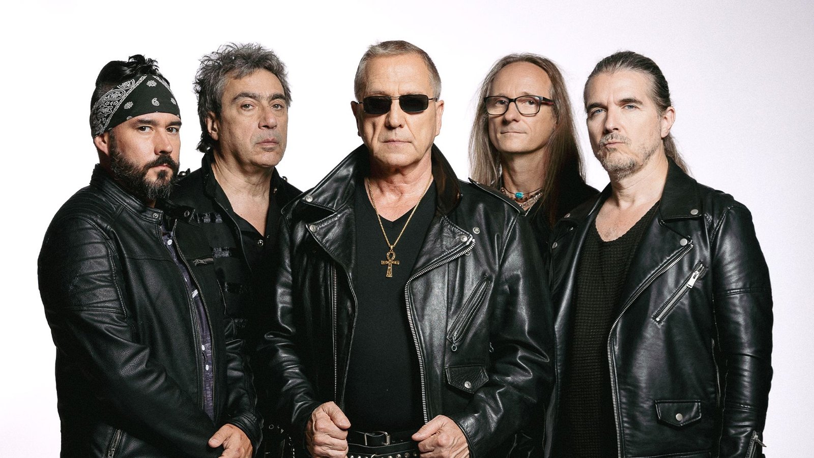 The five members of Sortilege photographed together in leather jackets against a white background