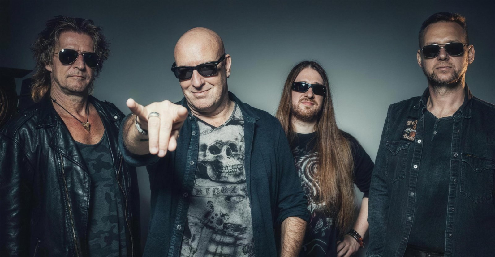 The four members of Iron Savior in a studio portrait, Piet Sielck at the front pointing at the camera