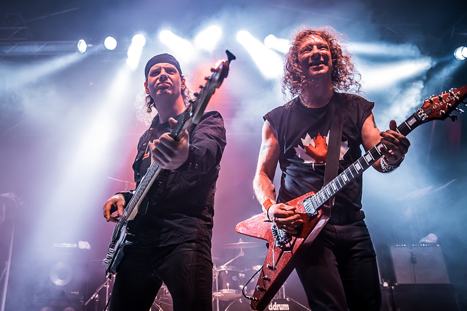 Anvil performing live at Musichall Geiselwind, Germany, 23 April 2016, two members playing guitar and bass on stage, one in a Canadian flag shirt
