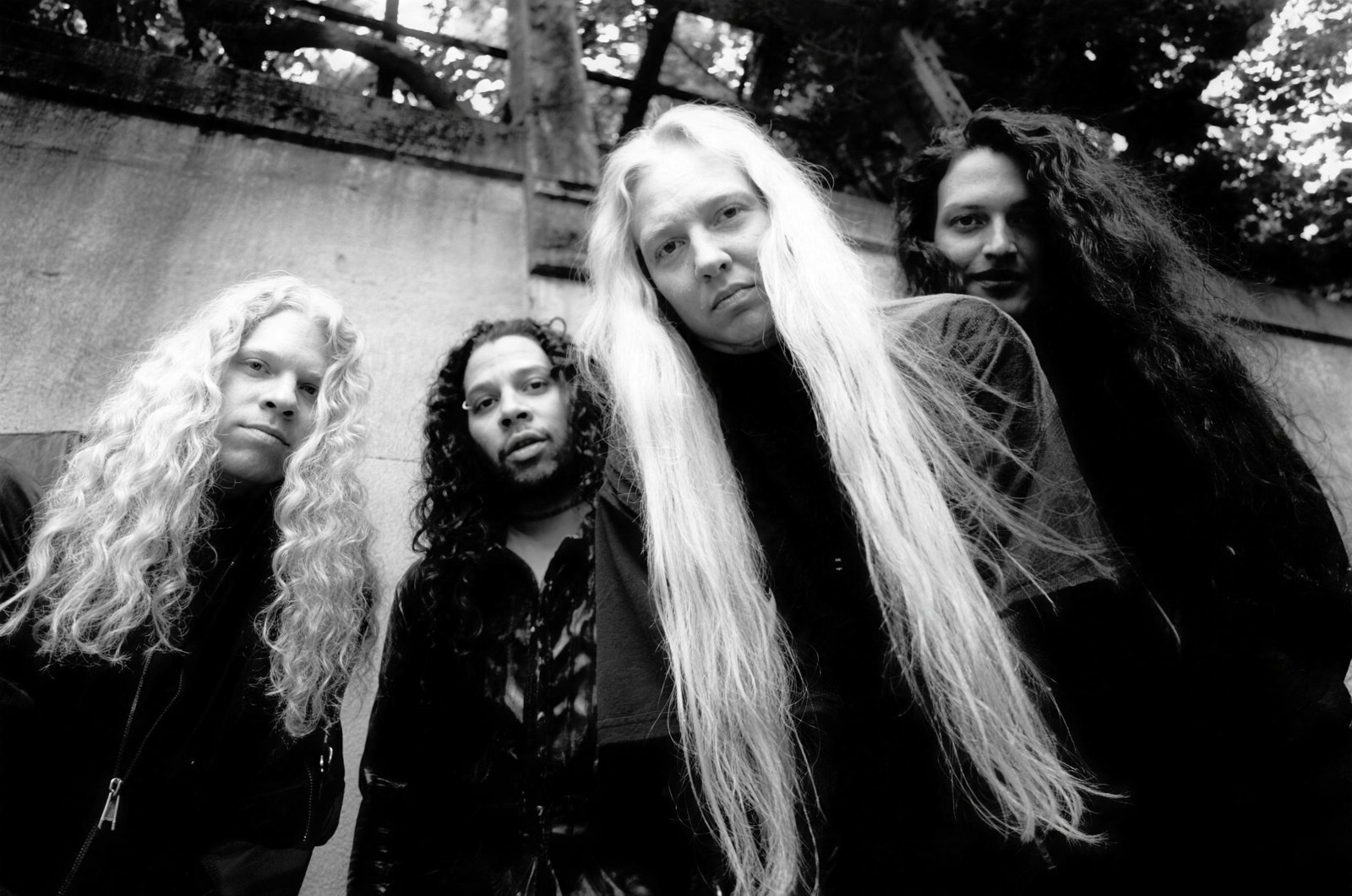 Nevermore, the four-piece band photographed outdoors in black and white during the Politics of Ecstasy era, long hair and dark clothing against a concrete wall