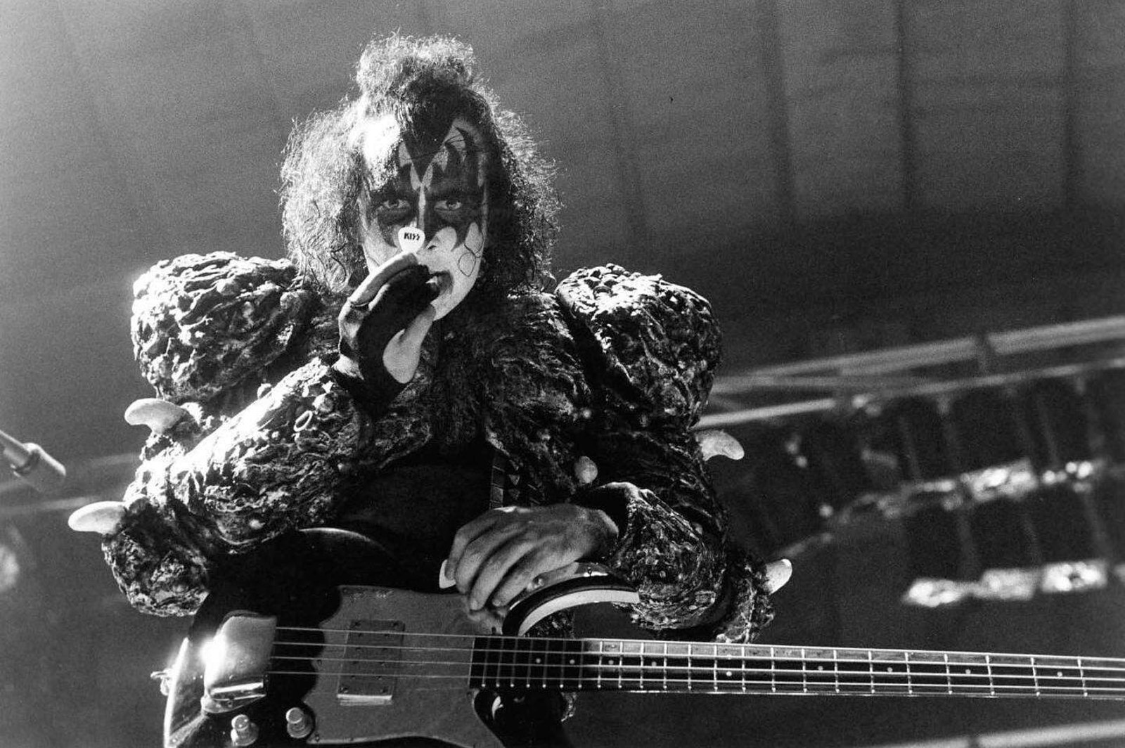 Gene Simmons of Kiss in full Demon greasepaint playing bass on stage in 1980