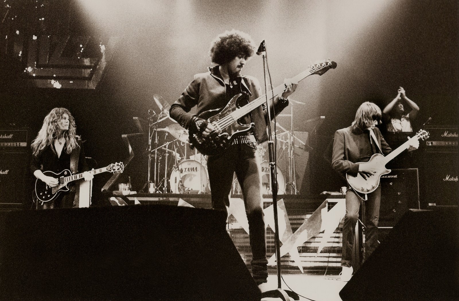 Phil Lynott of Thin Lizzy at the microphone with his mirrored bass at the Manchester Apollo in 1983, the band around him