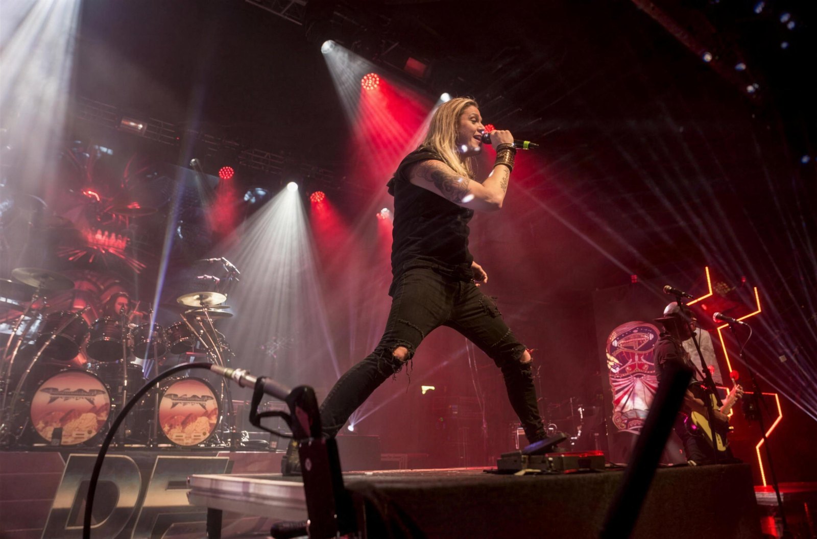 Marc Hudson of DragonForce leaping across the stage past the dragon-head kick drums, Kentish Town Forum, London, 8 November 2019.