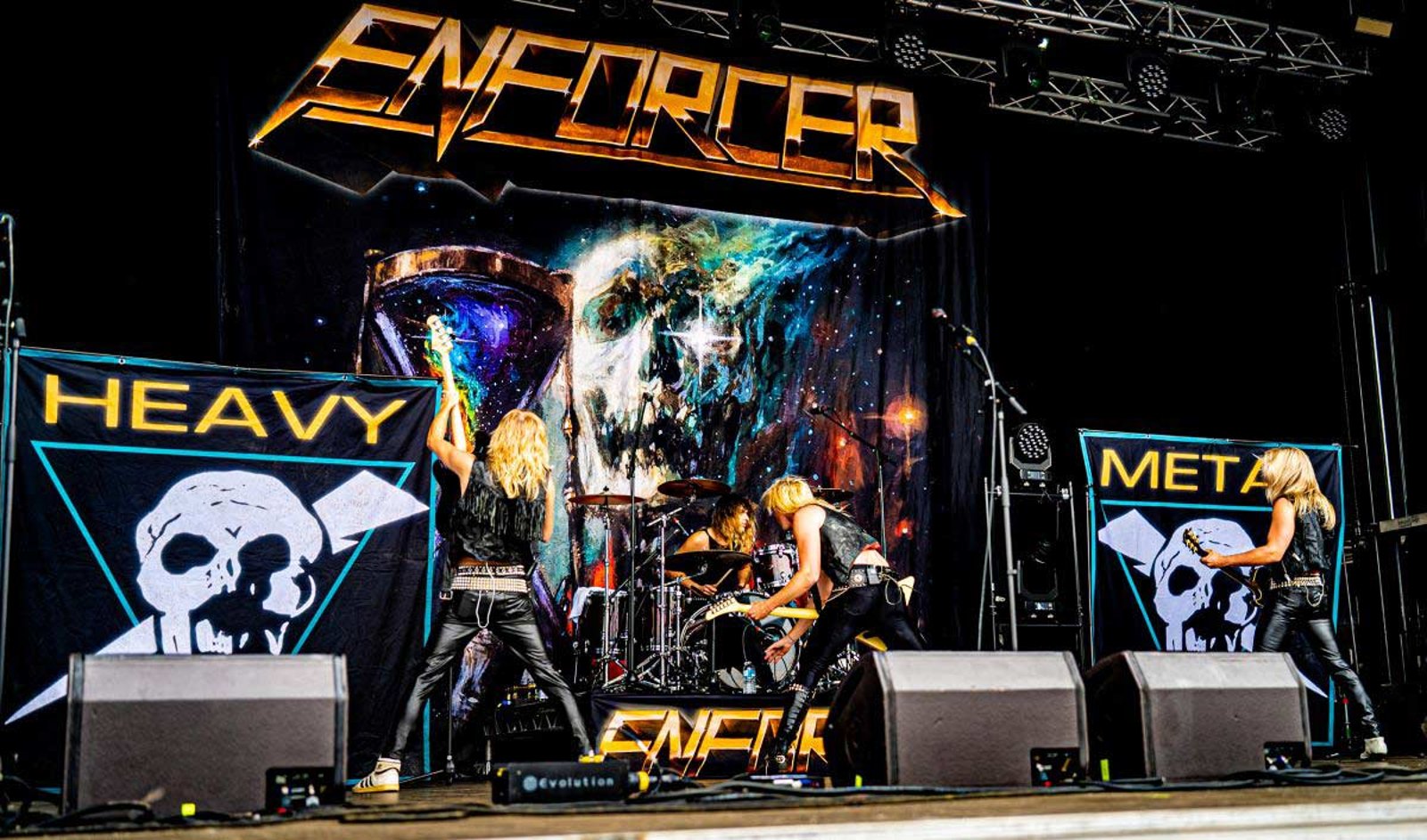 Enforcer on stage at Stonedead Festival in August 2025, between two banners reading heavy and metal