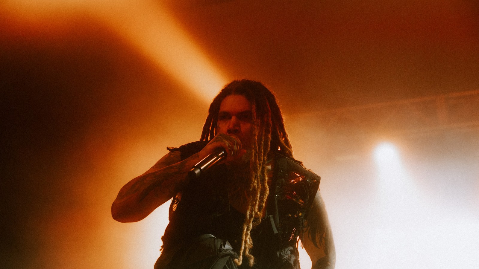 Brand of Sacrifice's vocalist singing into the microphone in orange stage haze at O2 Academy Birmingham, 2025.