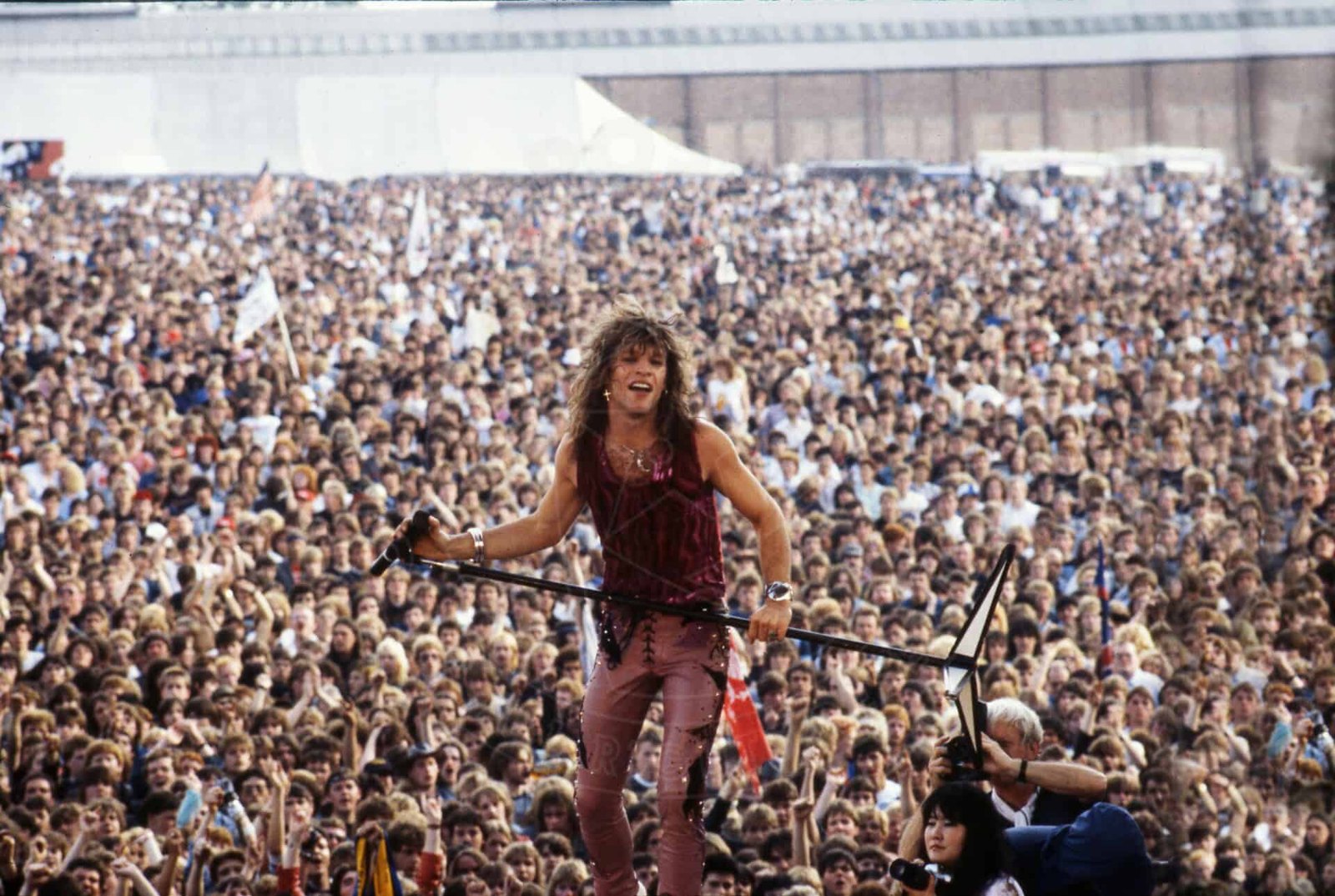 Jon Bon Jovi performing live before a massive festival crowd, 1980s