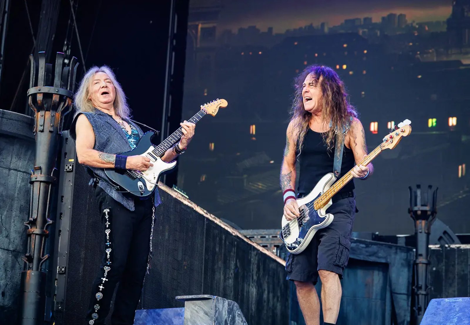Dave Murray playing guitar and Steve Harris playing bass side by side at the front of a festival stage