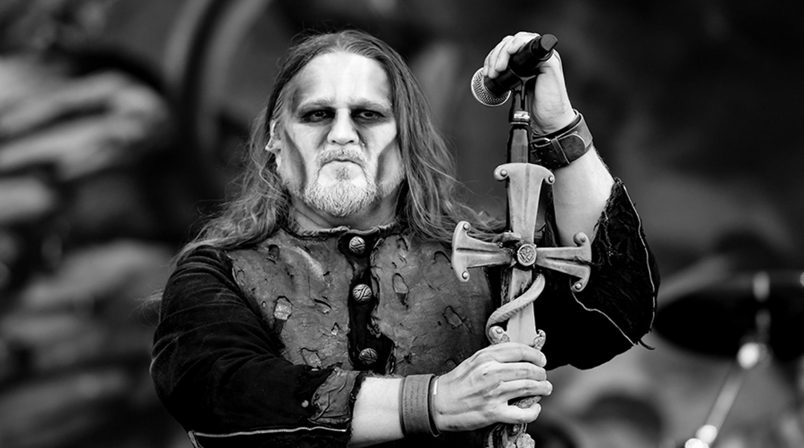 Powerwolf singer Attila Dorn in face paint, holding a microphone stand shaped like a cross, Sweden Rock Festival 2019