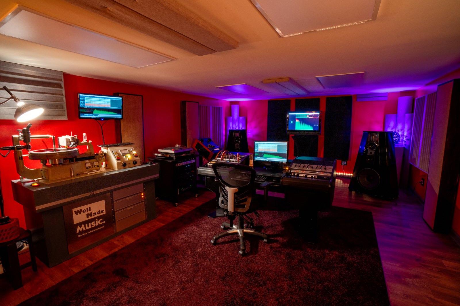 A mastering room with a cutting lathe on the left and two screens carrying waveform and spectrum readouts