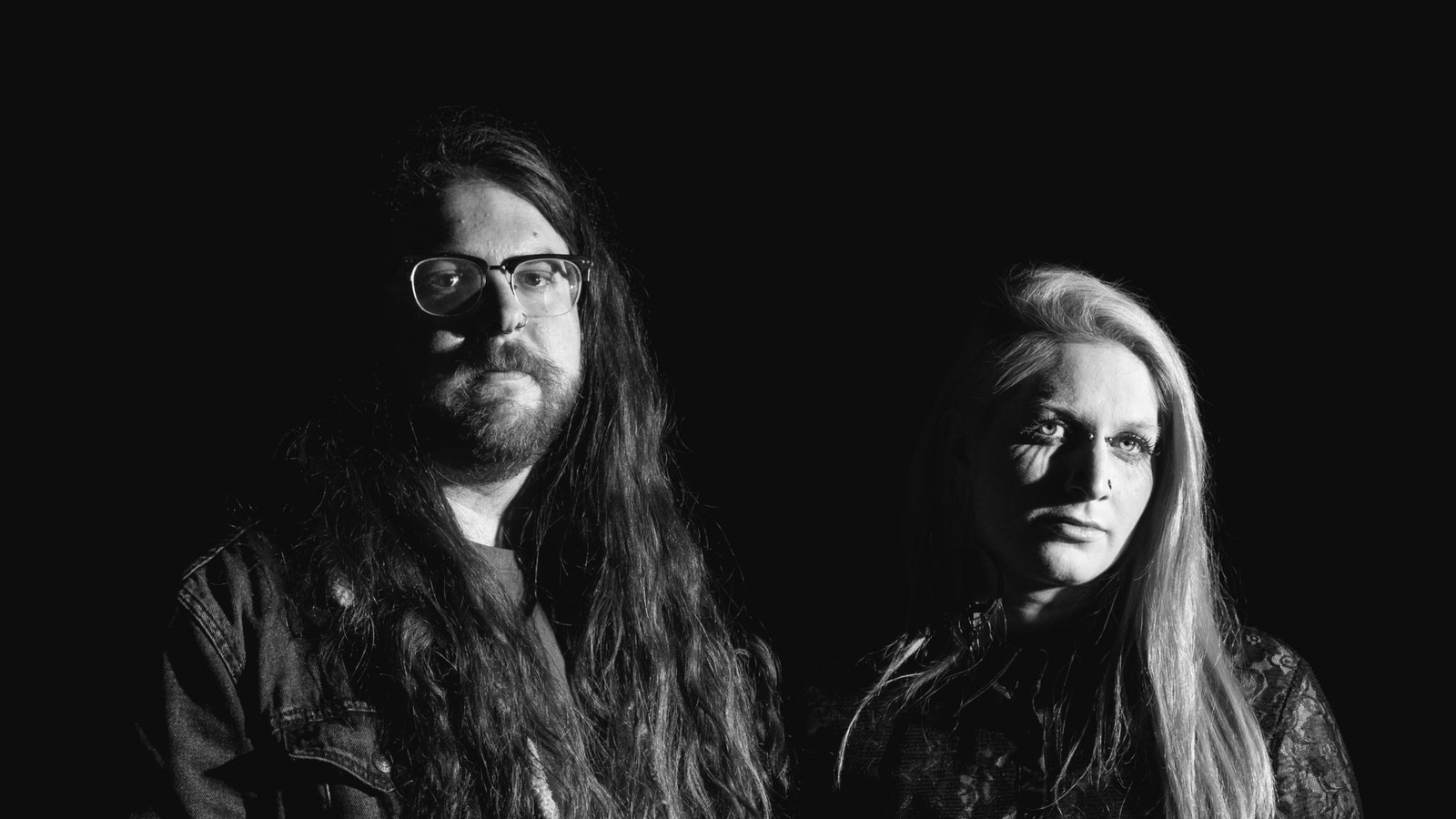 The two members of Vile Creature lit from the side against a black background, in black and white