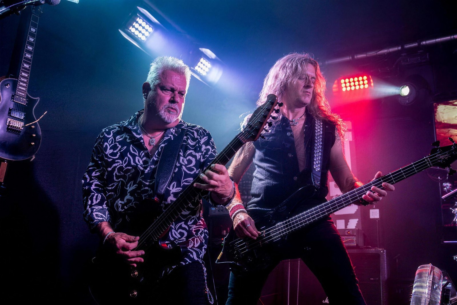 Robb Weir and the bassist of Tygers of Pan Tang performing live on stage at The Patriot Home of Rock, Rotherham, 4 August 2023, guitar and bass in hand under blue and red stage lighting