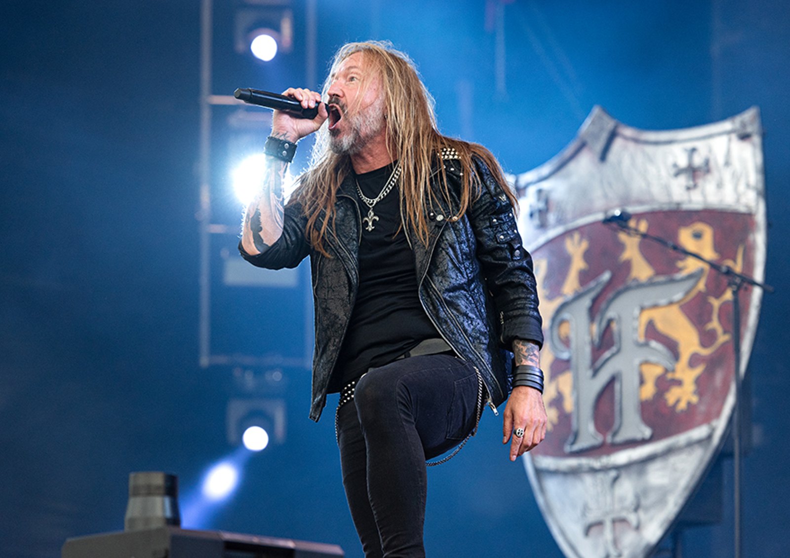 HammerFall singer Joacim Cans performing live in front of the band's shield emblem backdrop