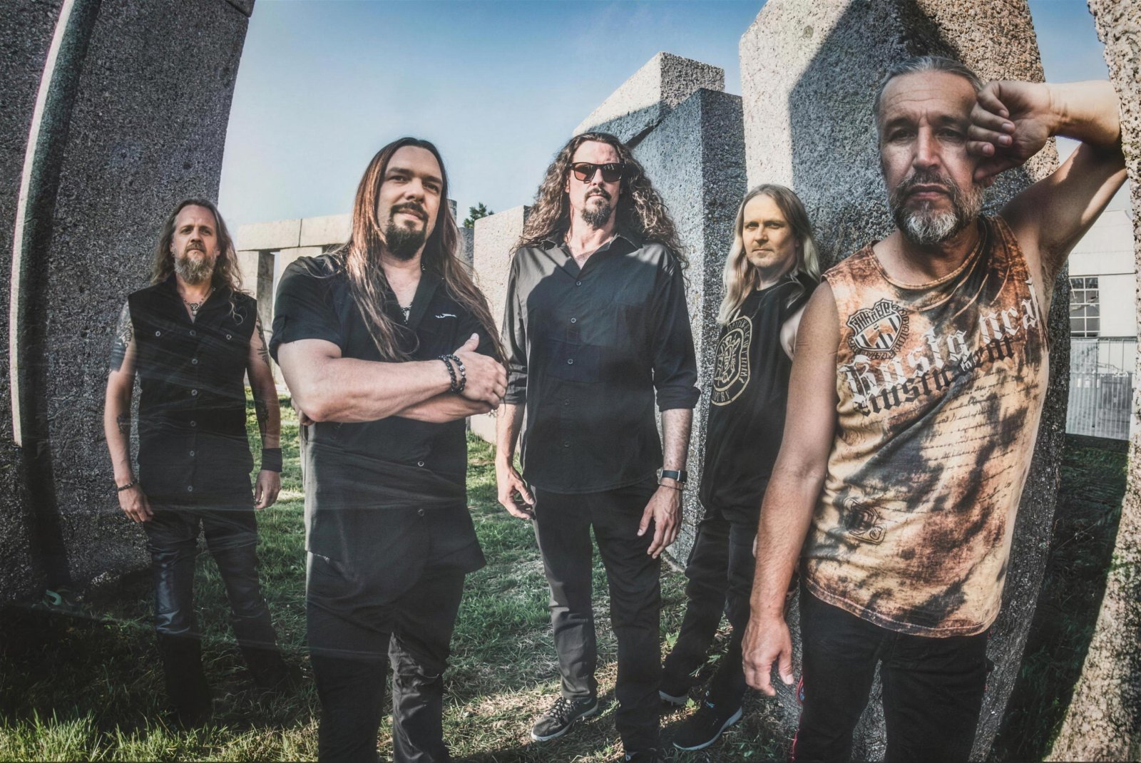 Sonata Arctica's five members standing together among tall stone monuments in a promotional portrait made for the band's thirtieth anniversary