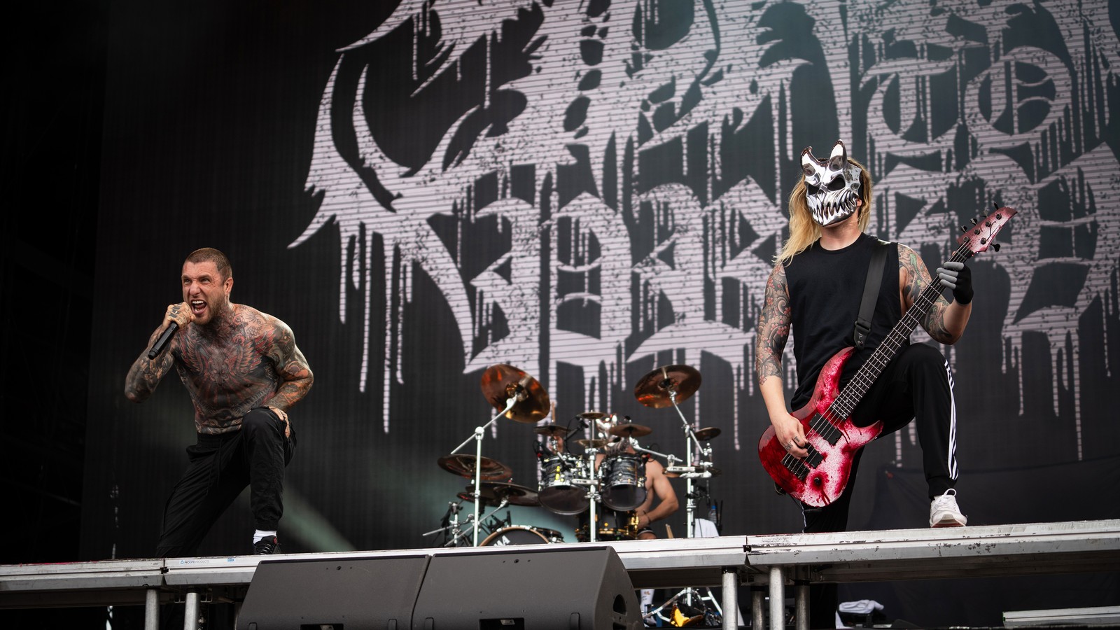 Slaughter to Prevail on the main stage at Hellfest 2024: vocalist Alex Terrible screaming into the microphone on the left, the drummer in the middle and a masked bassist on the right, in front of the band's logo backdrop.