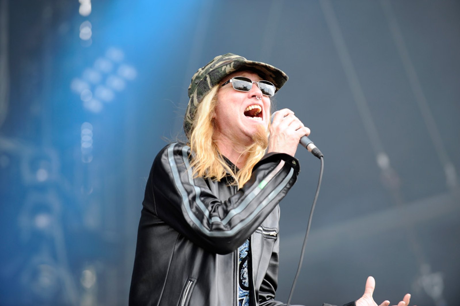 Warrel Dane of Sanctuary singing into a handheld microphone on a blue-lit festival stage at Wacken Open Air, 2012