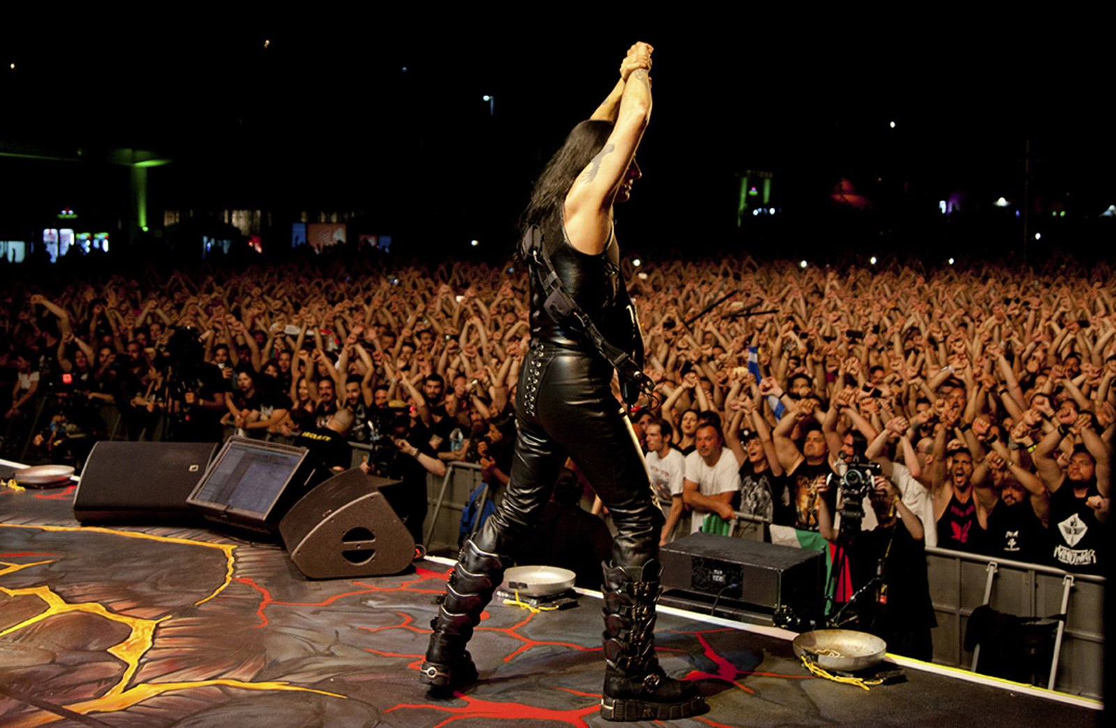 Manowar on stage in 2019, arms raised in front of a packed field