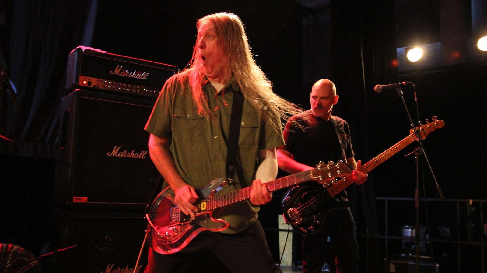 Fu Manchu on stage in Cologne, the long-haired guitarist in a green shirt and the bassist behind him, Marshall amplifiers at the side