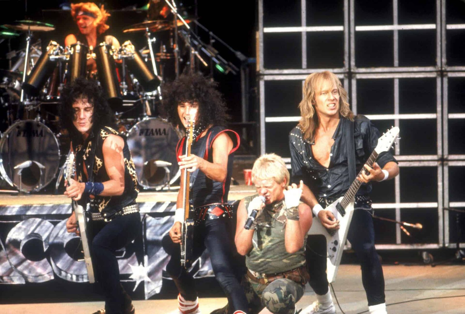 Accept playing an open air stage, the singer crouched at the microphone in a camouflage top, two guitarists either side of him and the drummer on a riser behind
