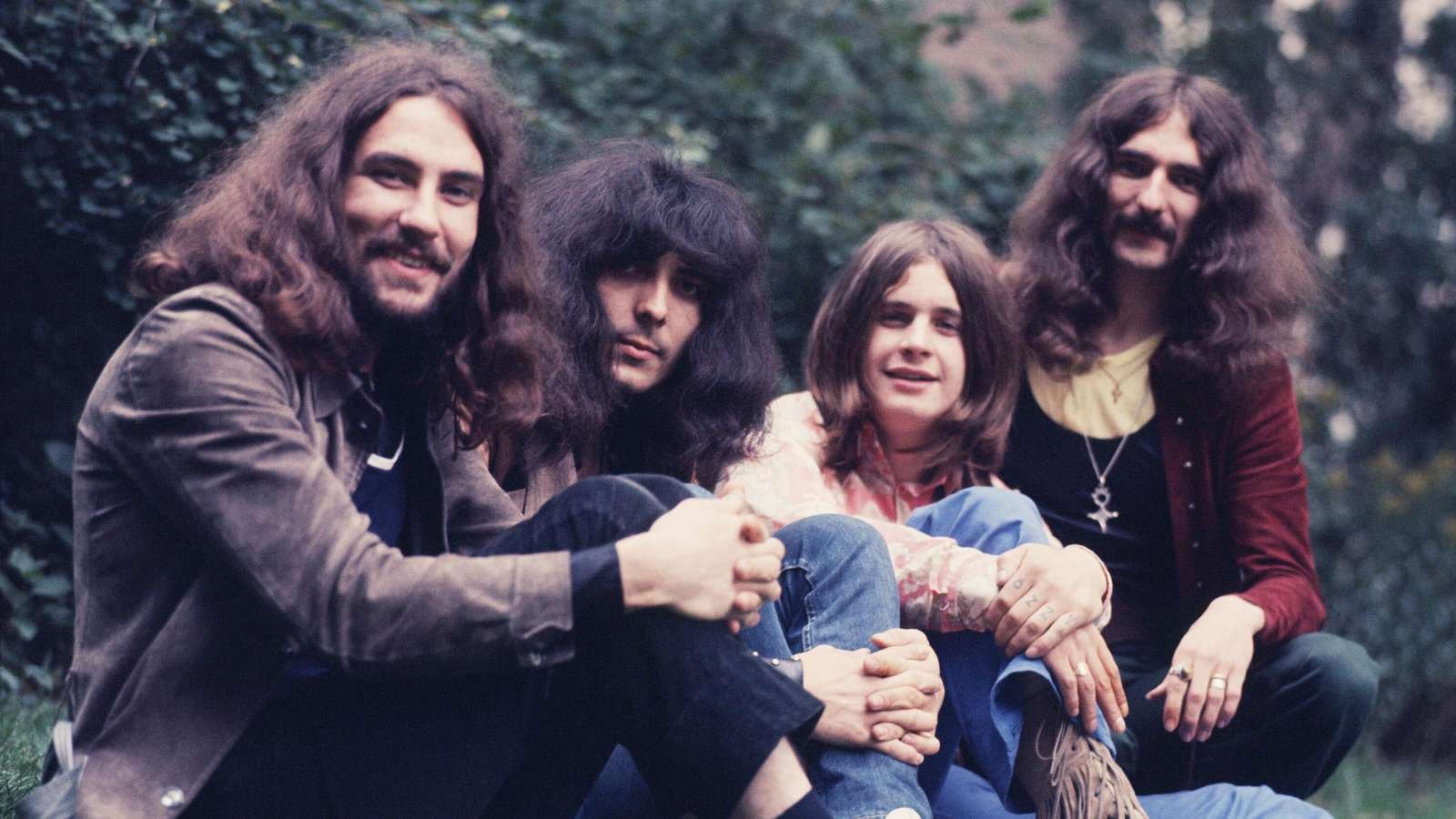 Black Sabbath outdoors in 1970, Bill Ward, Tony Iommi, Ozzy Osbourne and Geezer Butler sitting together for a color group portrait