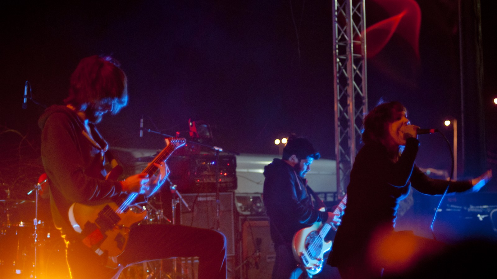 Iwrestledabearonce on an open-air stage in Lubbock, Texas, in 2011: a guitarist and a bassist on the left and centre, the singer on the right with the microphone at her mouth and her arm stretched out